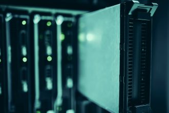 Fileiras de racks de servidores em um datacenter moderno, iluminadas por luzes azuis.