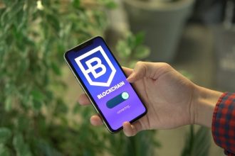 Mão segura um smartphone que exibe a tela de um aplicativo de blockchain.